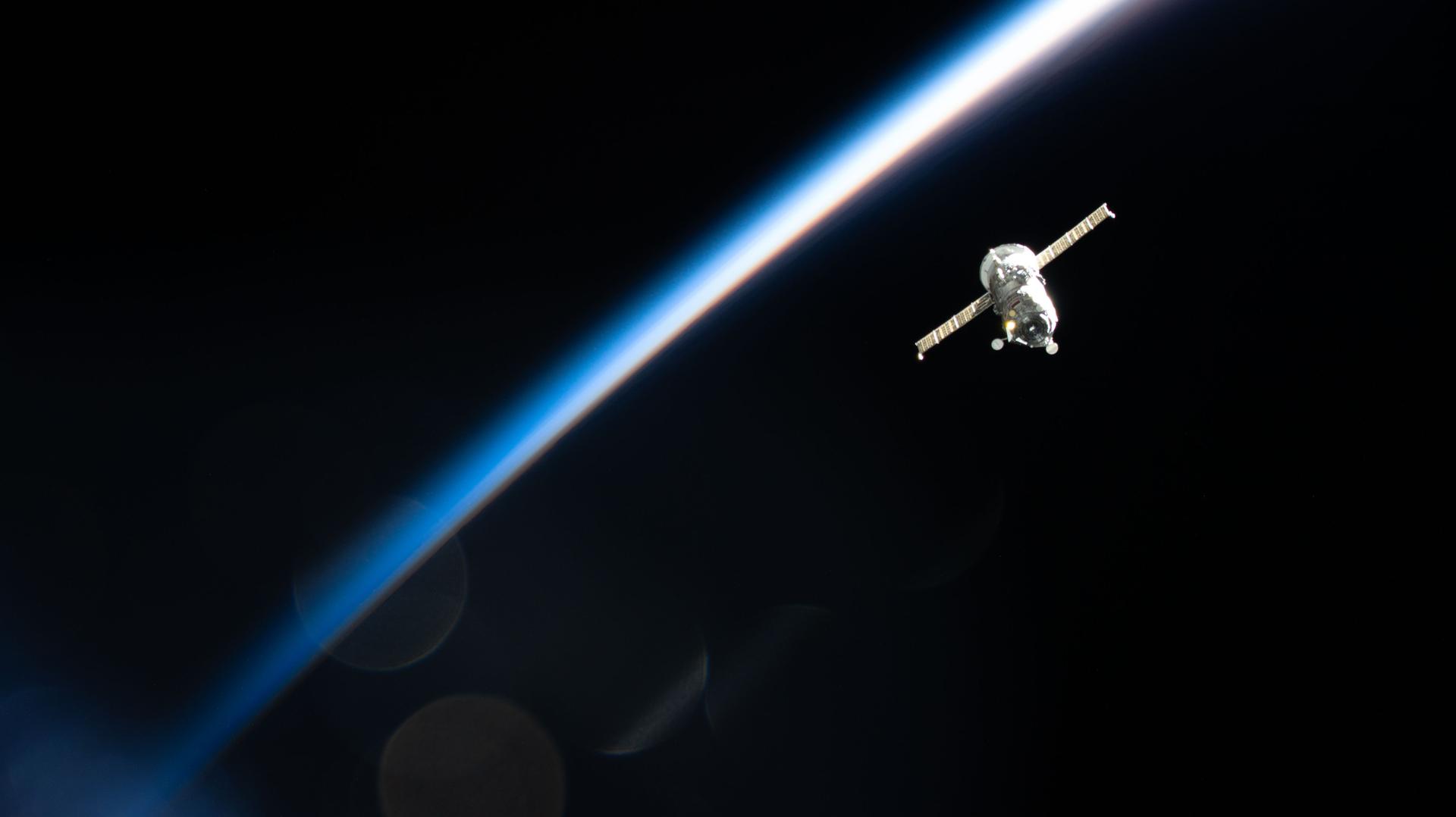 货运飞船离开国际空间站，远处可见轨道日落与地球弧线。